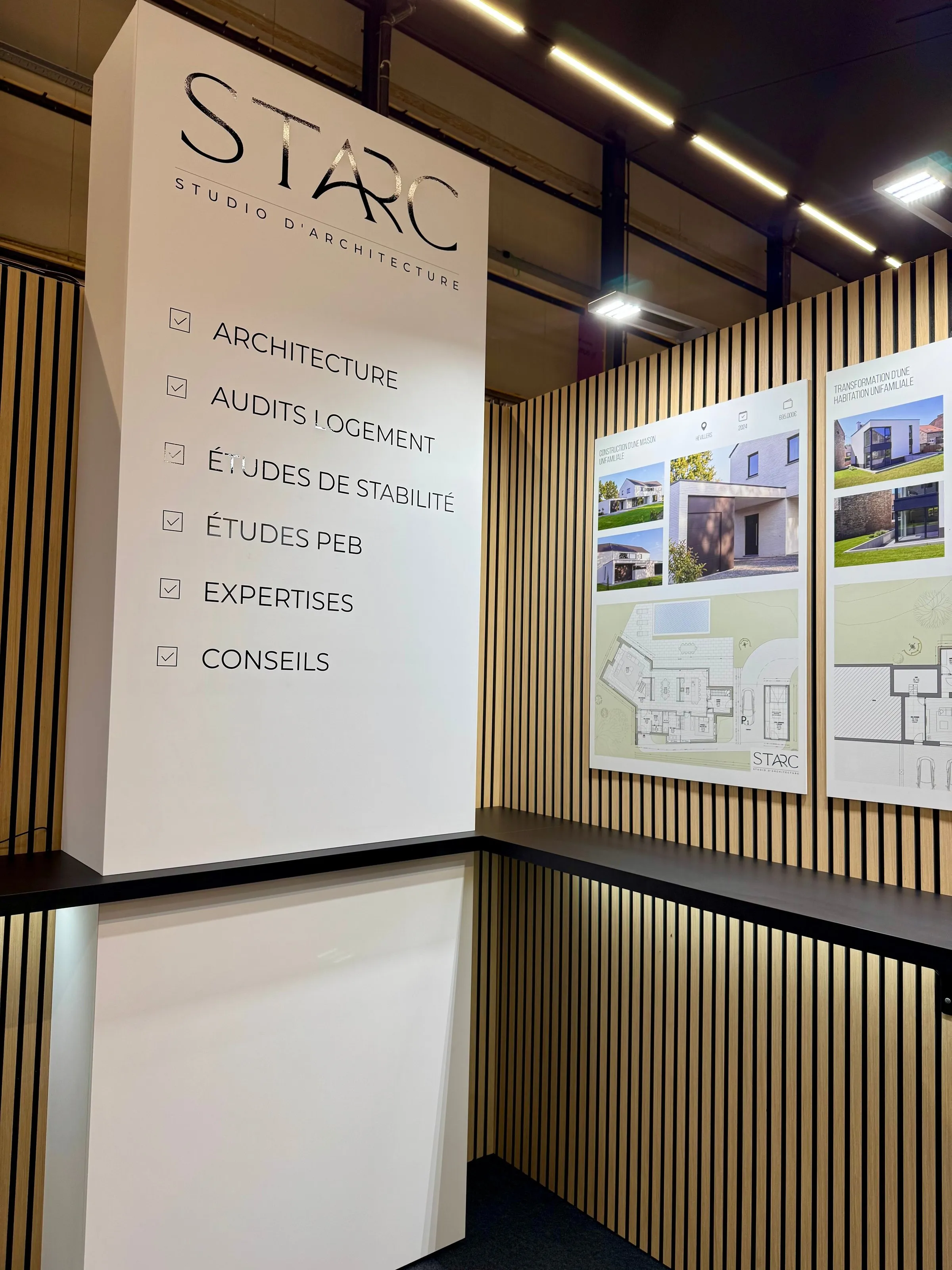 Totem STARC et panneaux de projets sur murs à lattes